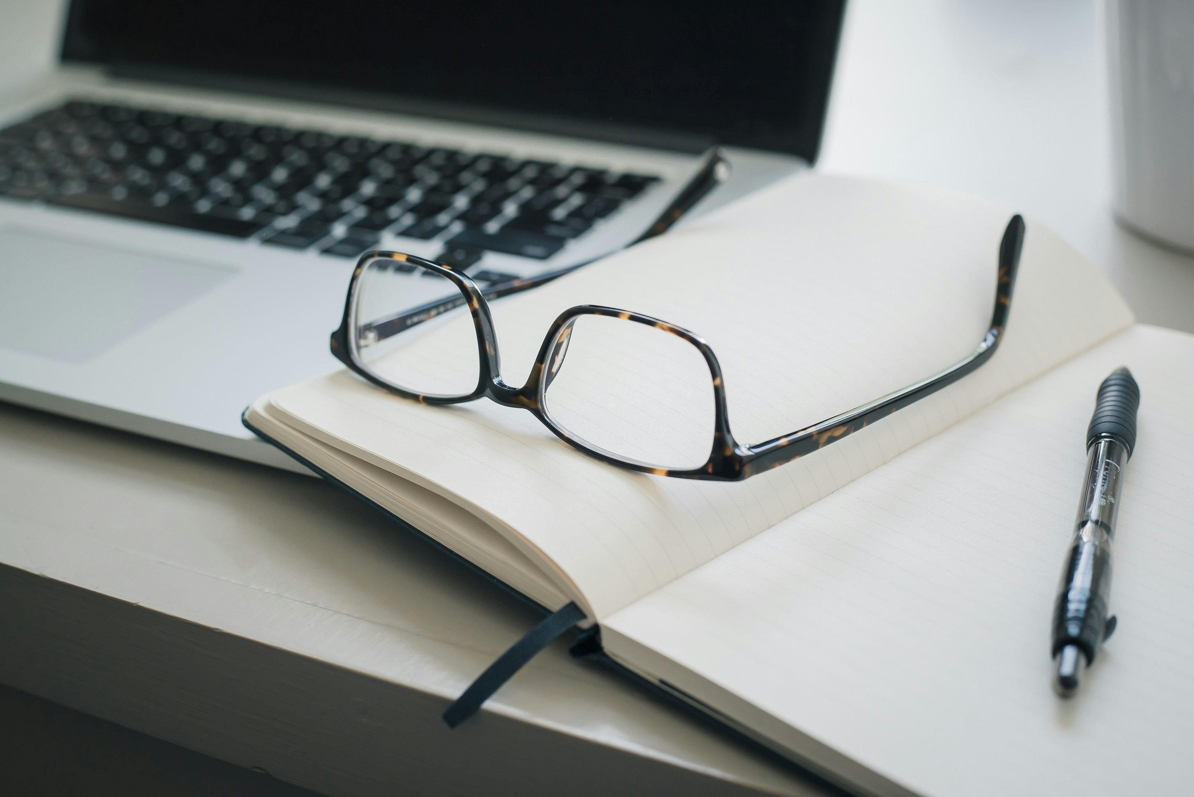 Notebook and glasses on a desk supporting the role of content pages in Shopify conversions