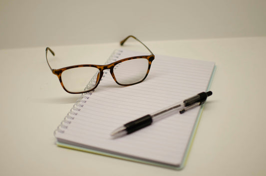 Notebook, glasses, and pen supporting the long-term cost of good enough Shopify decisions